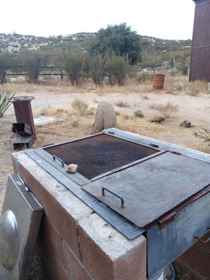 El asador al aire libre, con su parrilla, y el campo detrás.