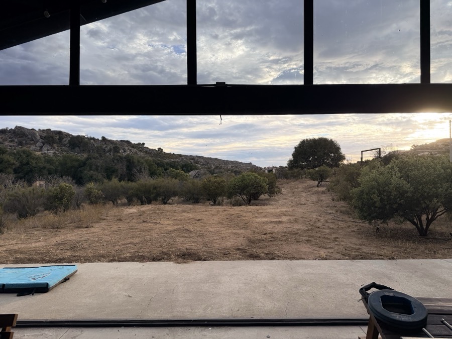 La vista desde la nave al atardecer: el campo abierto y las lomas de granito al fondo.